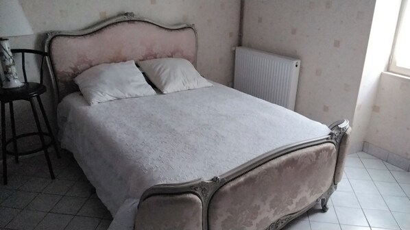 Et soveværelse med seng, stol og radiator.