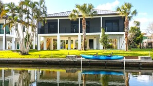 A modern building with a covered outdoor area, a small boat, and a canal.