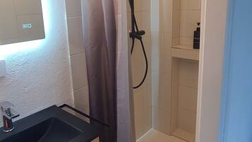 Een douche, handdoeken, zeep, toiletpapier