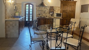 A kitchen with a dining table and chairs, a microwave, cabinets, and a wooden door.