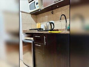 Eine kleine Küche mit Mikrowelle, Wasserkocher und Kühlschrank.