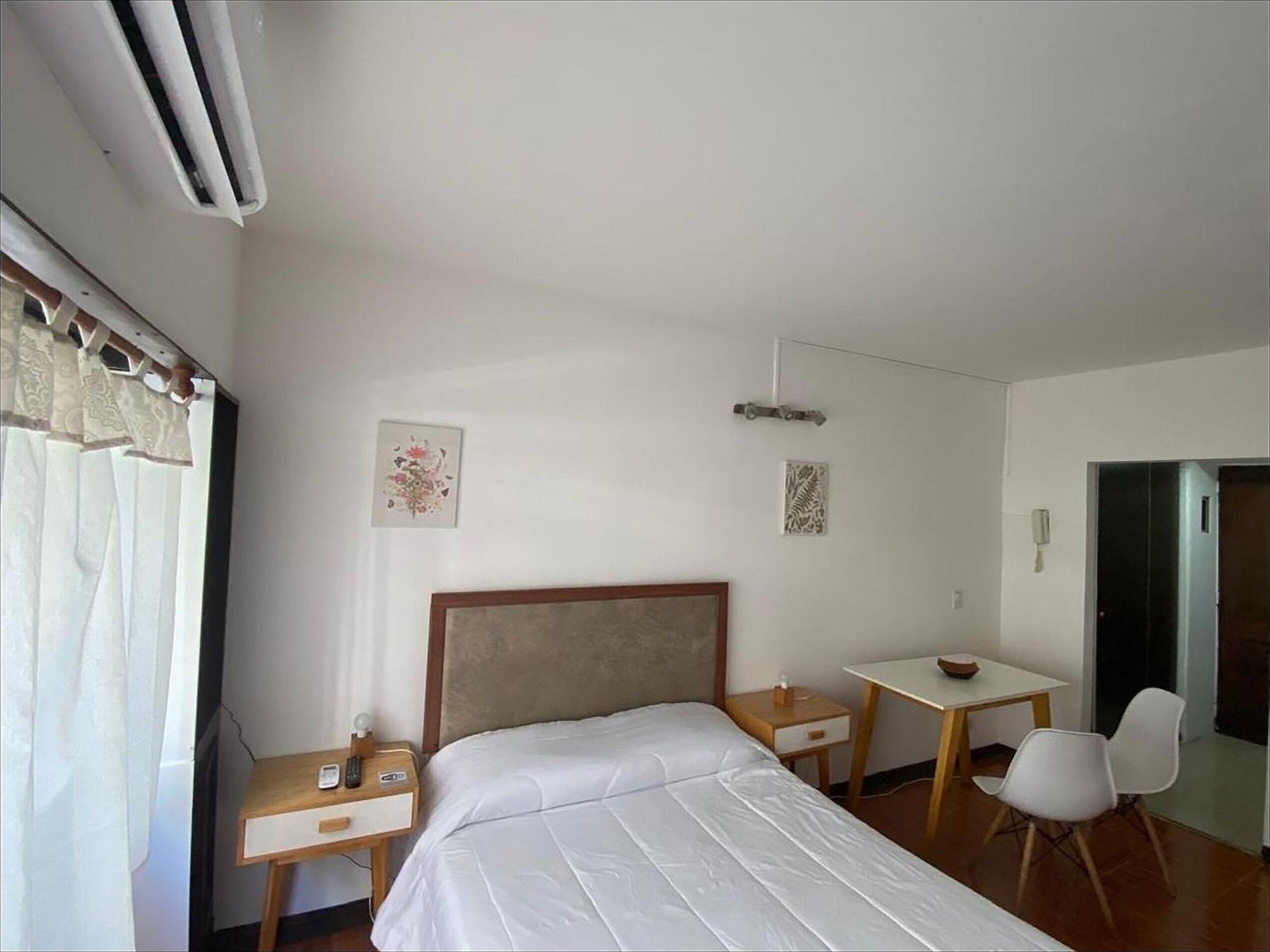 Une chambre d’hôtel avec un lit, un bureau, une chaise et une petite table.