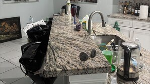 A kitchen with a granite countertop, white cabinets, and a window with a wreath. - All Inclusive Hotel- Montego Bay, Jamaica (Montego Bay)