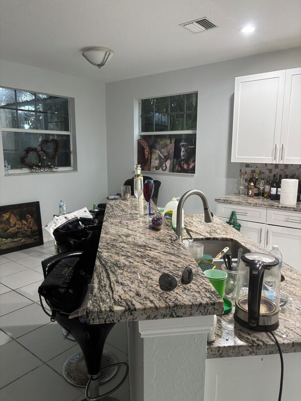 A kitchen with a granite countertop, white cabinets, and a window with a wreath.