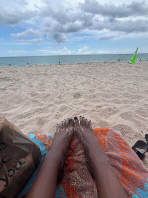 Une scène de plage avec une serviette et un sac sur le sable.