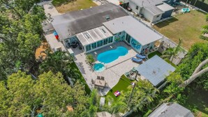 An aerial view of a modern house with a swimming pool, surrounded by lush greenery and a well-maintained lawn. - Tropical Oasis Heated Pool • Spa • Pool Table • Grill • Games • Beach 15 Minutes (Seminole)