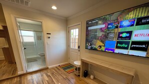 Een woonkamer met een grote flatscreentelevisie aan de muur, waarop verschillende streamingdiensten te zien zijn.