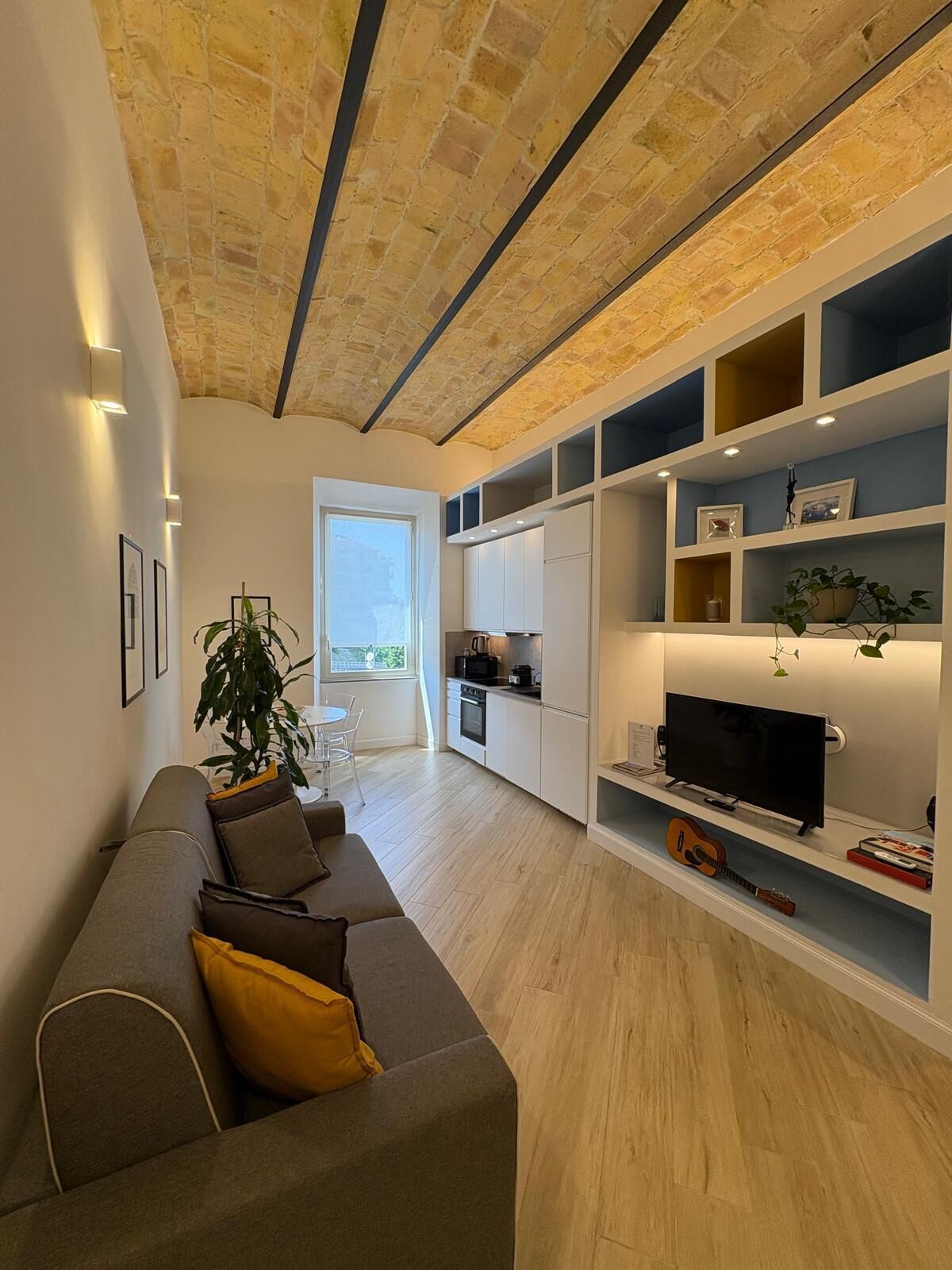 Una sala de estar moderna con un sofá gris, un televisor y estanterías empotradas.