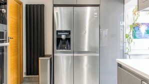 A modern kitchen with a stainless steel refrigerator, a water dispenser, and a trash bin.