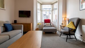 A modern living room with a sofa, a wooden coffee table, a chair, and a television mounted on the wall.