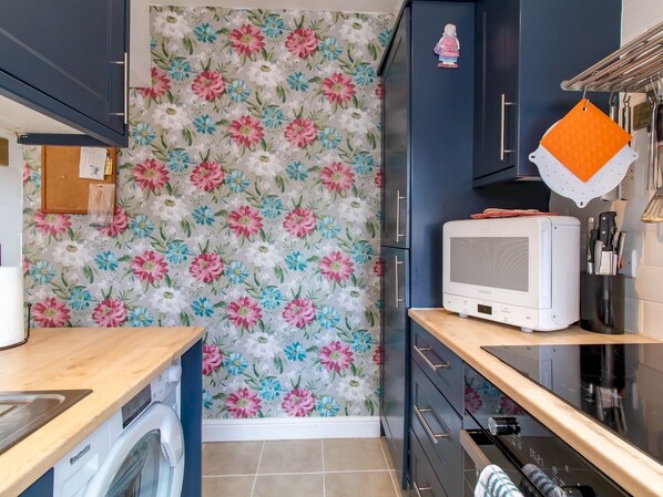 Una cocina compacta con lavadora, microondas y pileta.