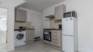 Una cucina compatta con lavatrice, forno e frigorifero.