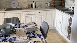 A kitchen with white cabinets, a dining table with a blue tablecloth, and a wall-mounted towel rack. - Apartment les saintes maries de la mer (Saintes-Maries-de-la-Mer)