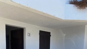 A white building with a wooden gate, a dark door, and a small window. - Apartment les saintes maries de la mer (Saintes-Maries-de-la-Mer)