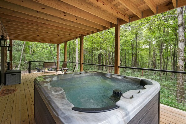 Un bain à remous sur une terrasse en bois, avec vue sur une forêt.