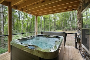 A hot tub on a wooden deck with a forest view.