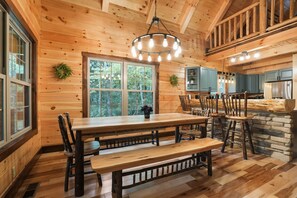 Un interior de madera con una gran mesa de comedor, bancos y una zona de cocina.