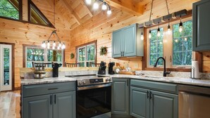 A modern kitchen with granite countertops, stainless steel appliances, and teal cabinetry.