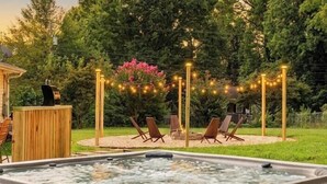 Un jacuzzi rodeado de asientos exteriores y luces colgantes.