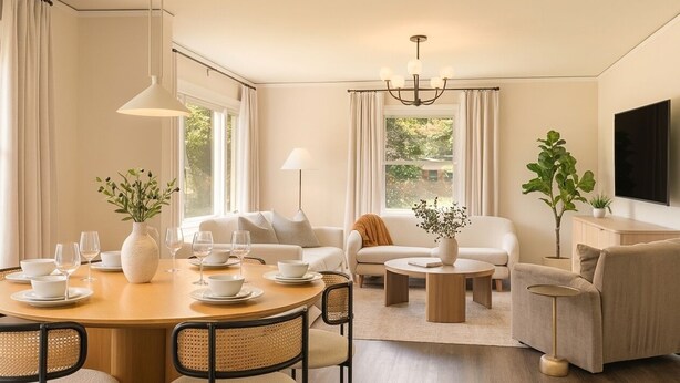 Una sala de estar moderna con comedor, sofás, una mesa de centro y un televisor.