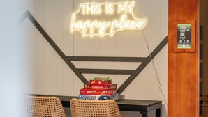 Un letrero de neón que dice 'THIS IS MY happy place' sobre una mesa con juegos de mesa.