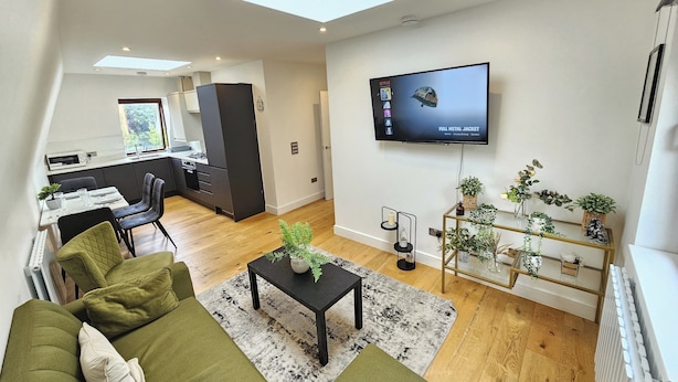 A modern apartment with a dining area, kitchen, living room, and a TV mounted on the wall. - City Retreat in Central London (London)