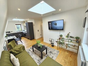 A modern apartment with a dining area, kitchen, living room, and a TV mounted on the wall. - City Retreat in Central London (London)