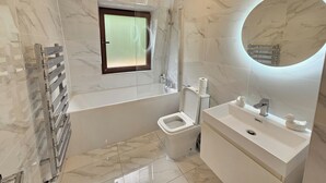 A modern bathroom with a bathtub, toilet, and sink. - City Retreat in Central London (London)