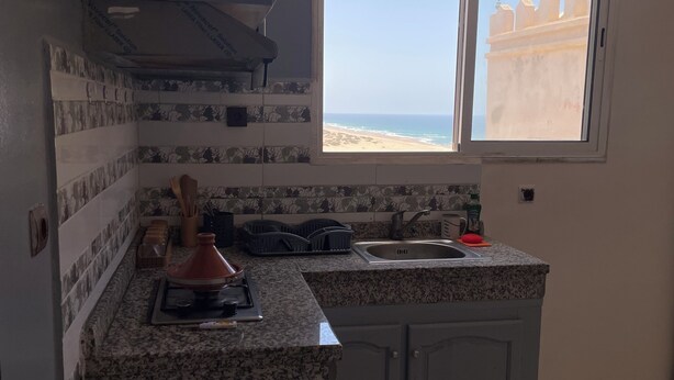 Cocina compacta con vista a la playa, un lavabo y una estufa.