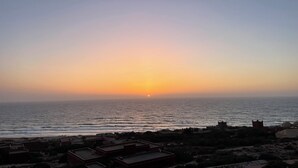 Vista de un atardecer costero con edificios en primer plano.