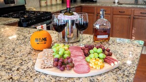 A kitchen counter with a charcuterie board, wine glasses, a bottle of wine, and a bottle of liquor. - Casa Bella -Sleeps 10 -Hot Tub + Fireplace- EV Charger - 5 Min to Ski Resort (Beech Mountain)