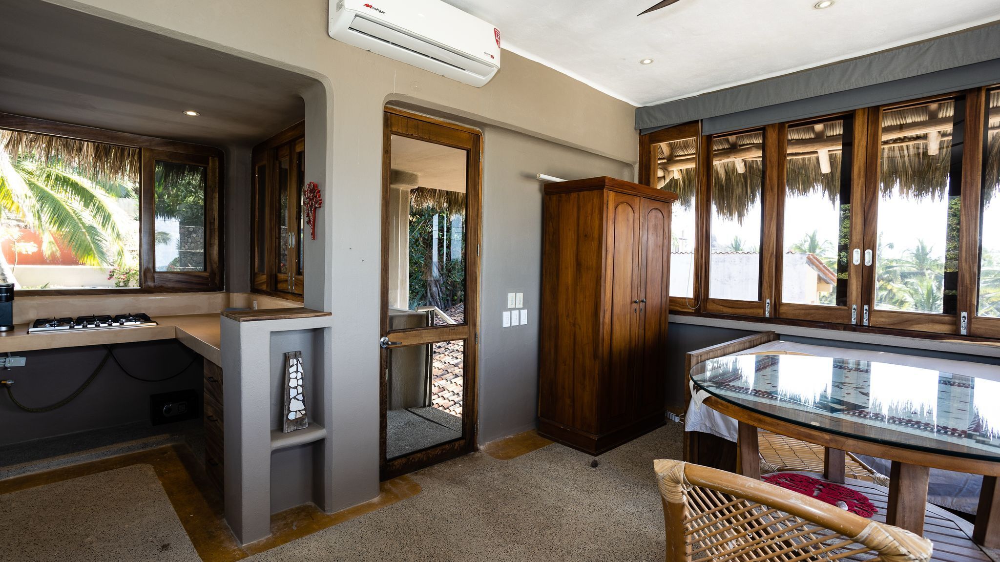 A modern kitchen with a gas stove, a built-in oven, and a large window overlooking a tropical garden.