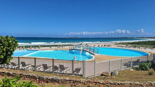 Un’area piscina con due piscine, lettini e vista sull'oceano.