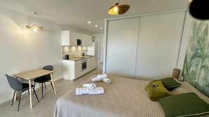 Una camera da letto moderna con un letto, cuscini, una scrivania e un angolo cottura.