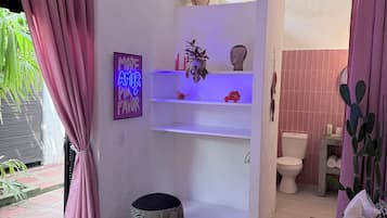 Un bagno moderno con un lavandino bianco, un WC e una zona doccia. Sul pavimento c'è un tappeto a motivi zebrati e una tenda rosa alla finestra.