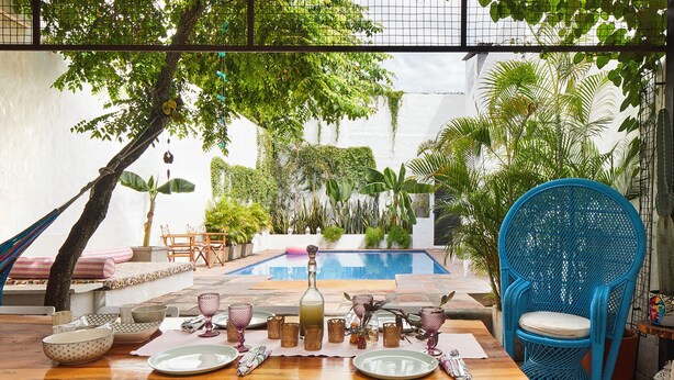 An outdoor dining area with a pool, surrounded by lush greenery and tropical plants. - Casa Amberes (Honda)