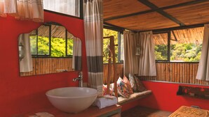 A bathroom with a large white sink, a mirror, and a window with curtains. - Casa Amberes (Honda)