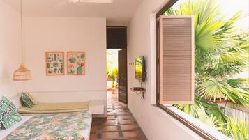 A room with a bed, a hanging light fixture, a TV mounted on the wall, and a window with blinds.