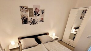 Una camera da letto ordinata con un letto, comodini, un armadio e decorazioni alle pareti.
