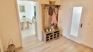 Un corridoio con una panca di legno, un appendiabiti e una porta con vetro satinato.