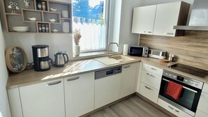 Una cucina moderna con mobili bianchi, forno integrato, microonde e macchina del caffè.
