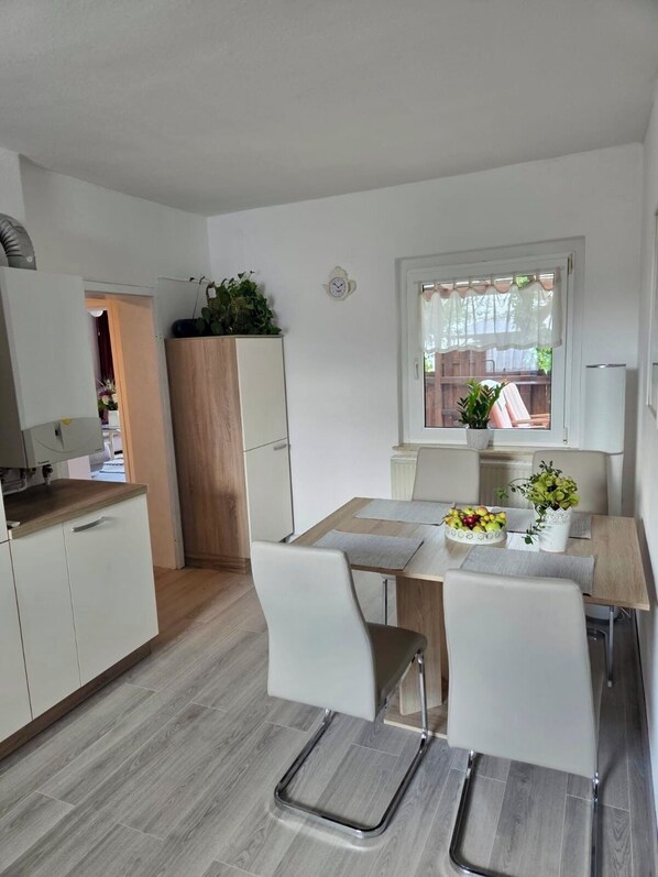A modern kitchen with white cabinets, a wooden countertop, and a dining area with a table set for two.
