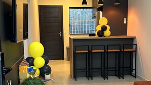 A modern kitchen with a wooden countertop, a built-in oven, and a window with a view of trees. - Your Sweet Home House in Içara near Criciúma!  A/C + bed with therapeutic massage+ (Içara)