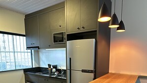 A modern kitchen with dark cabinetry, a stainless steel refrigerator, a wooden island, and pendant lighting. - Your Sweet Home House in Içara near Criciúma!  A/C + bed with therapeutic massage+ (Içara)