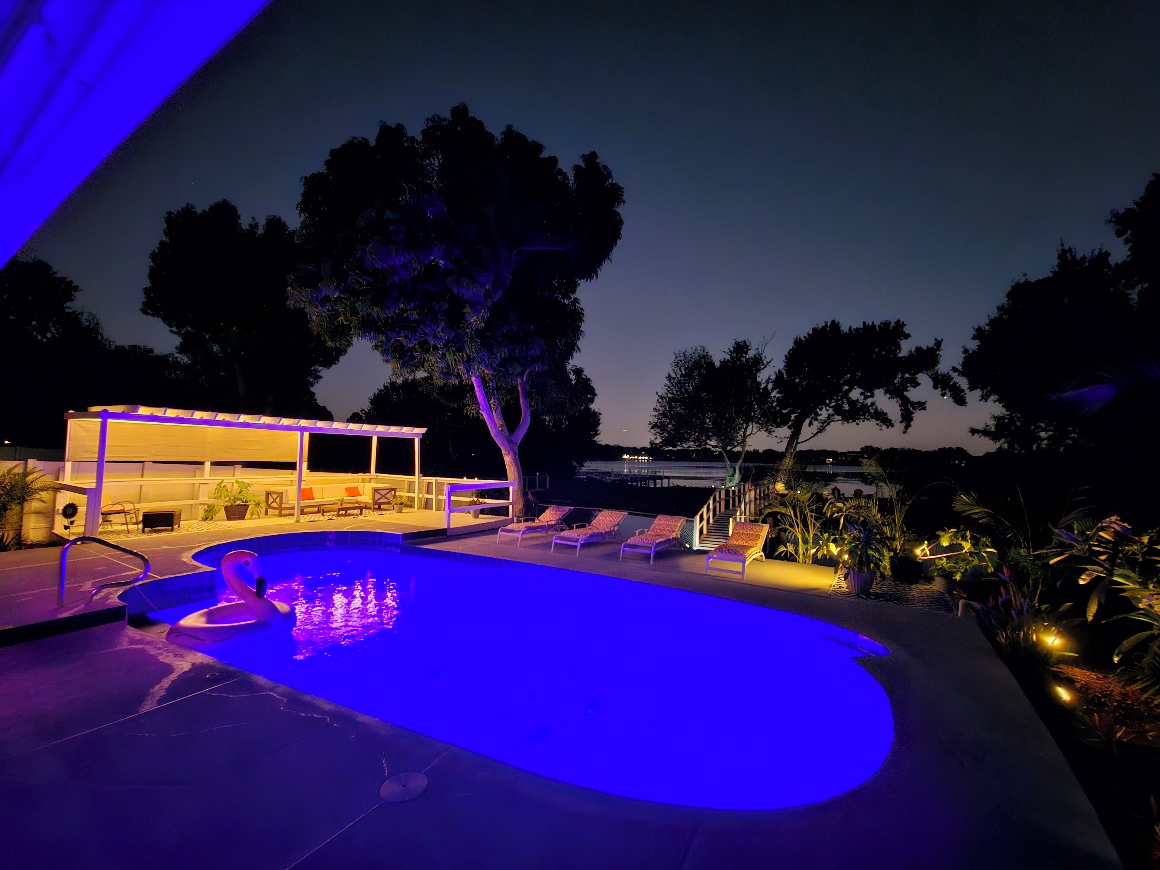 Zona de piscina exterior con área de estar techada y sillones de descanso.