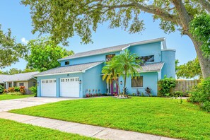 A two-story house with a blue exterior, a front garage, and a well-maintained lawn. - Lakefront retreat - Heated Pool - 8 miles to Clearwater beach (Clearwater)