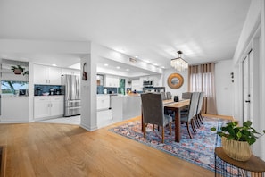 A modern kitchen with white cabinets, stainless steel appliances, and a blue backsplash.