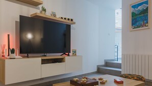 En moderne stue med et fladskærms-tv, træmøbler og et spillebord.