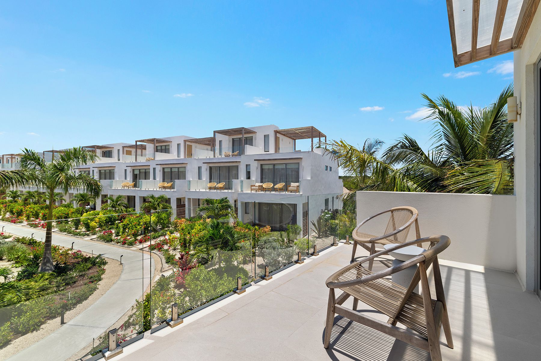 A modern hotel with multiple balconies, lush gardens, and a clear view of the surrounding area.