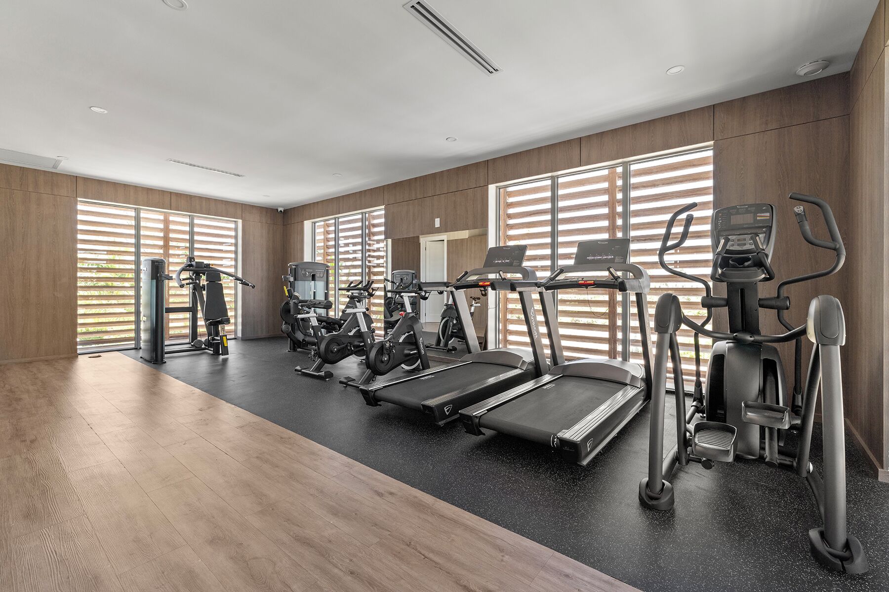 A modern gym with treadmills, elliptical machines, and weight equipment.
